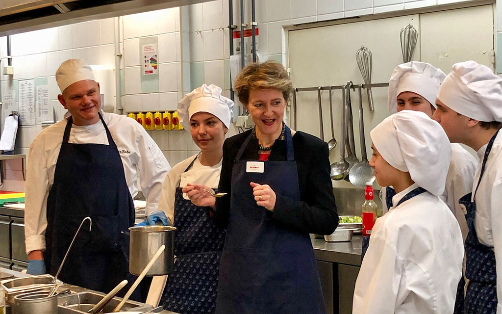 La conseillère fédérale Simonetta Sommaruga est dans une cuisine avec de jeunes aspirants cuisiniers qui effectuent, dans le cadre d’un projet, un apprentissage selon le modèle suisse.